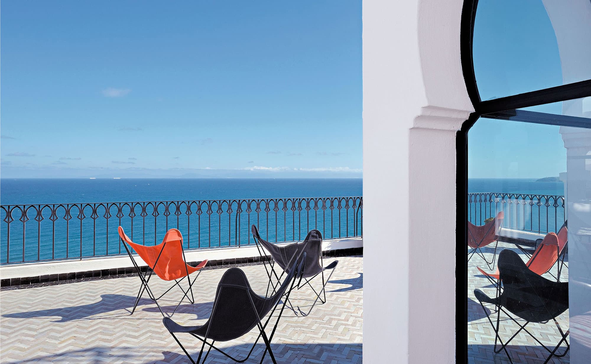 This balcony scene at the Nord Pinus Tangier captures a clear day over the Mediterranean, with designer chairs set against the backdrop of the expansive blue waters.