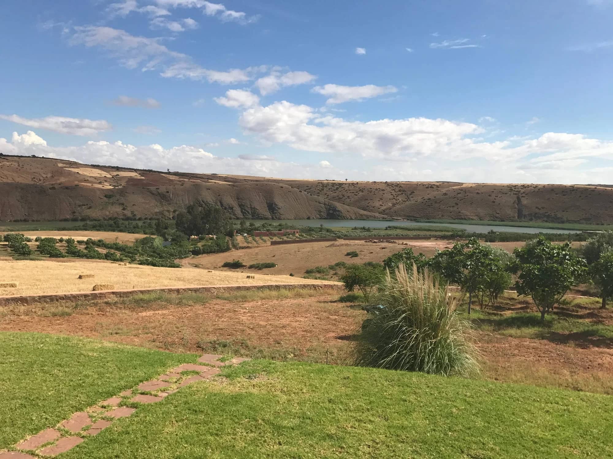 Lush landscape of Kasbah Oum Rabia inviting visitors to explore the tranquil river, rolling hills, and vibrant greenery, perfect for those looking to visit Kasbah Oum Rabia and experience the beauty of Morocco's countryside