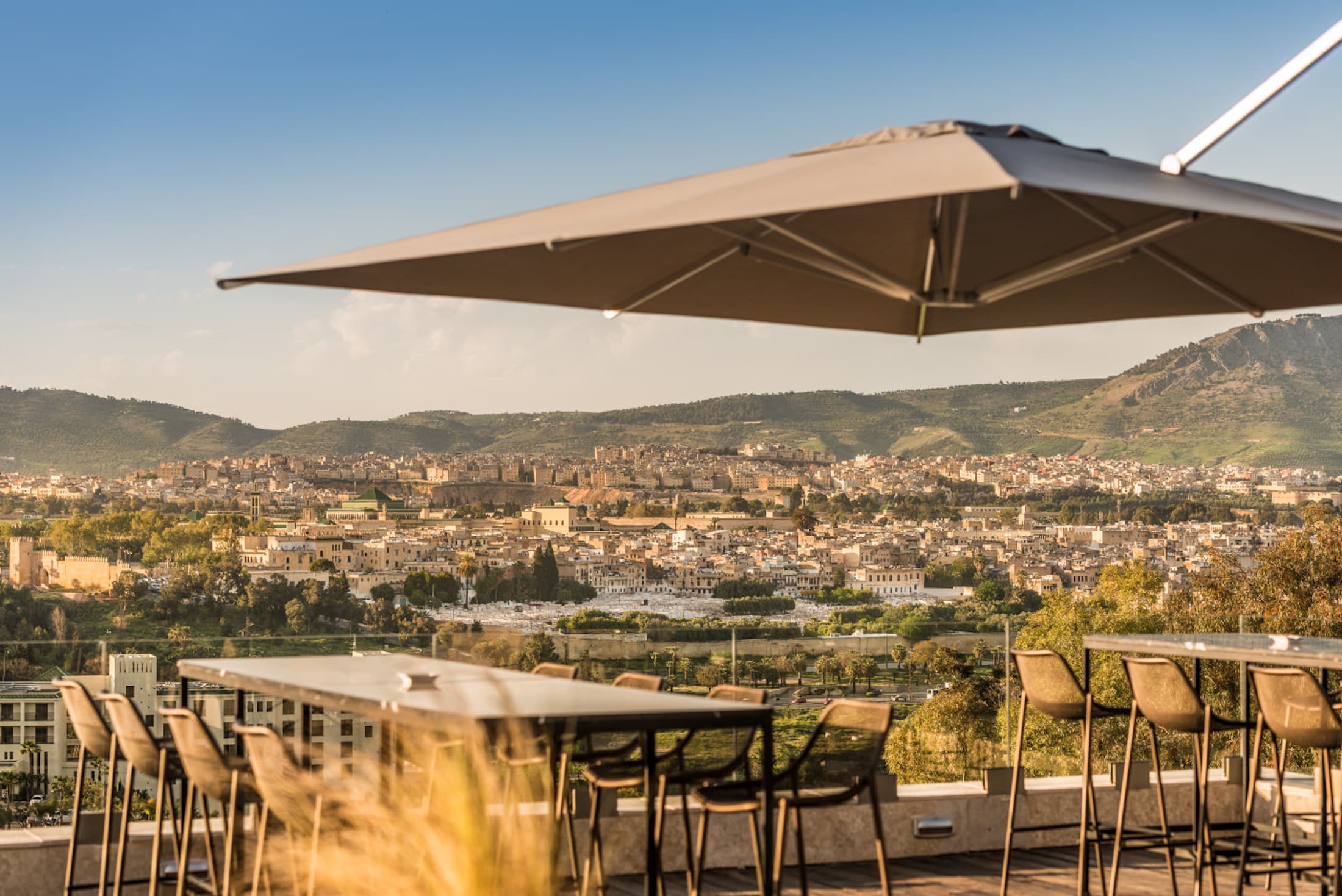 Hotel Sahrai rooftop in Fes featuring elegant outdoor seating under a parasol with panoramic views of the city.