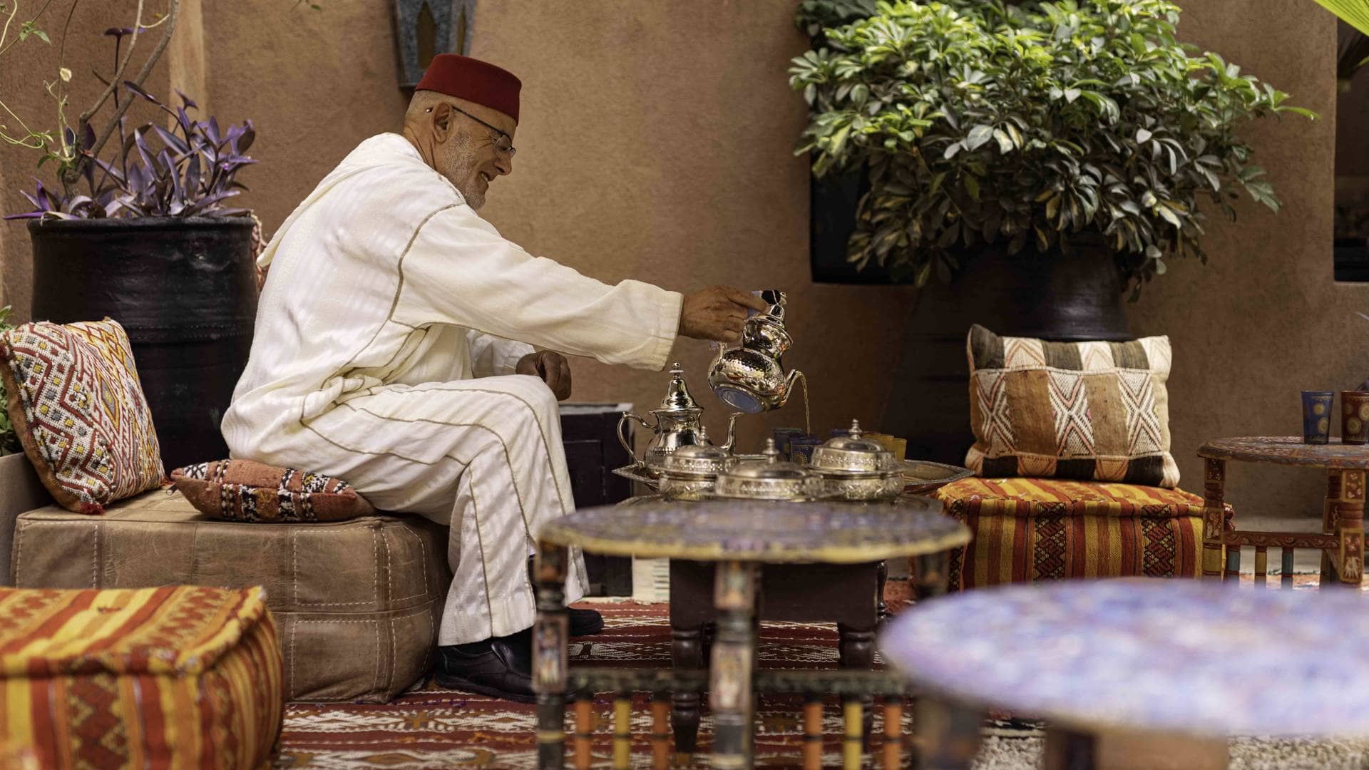 A traditional Moroccan mint tea ceremony, featuring a man pouring tea from a beautifully ornate teapot.