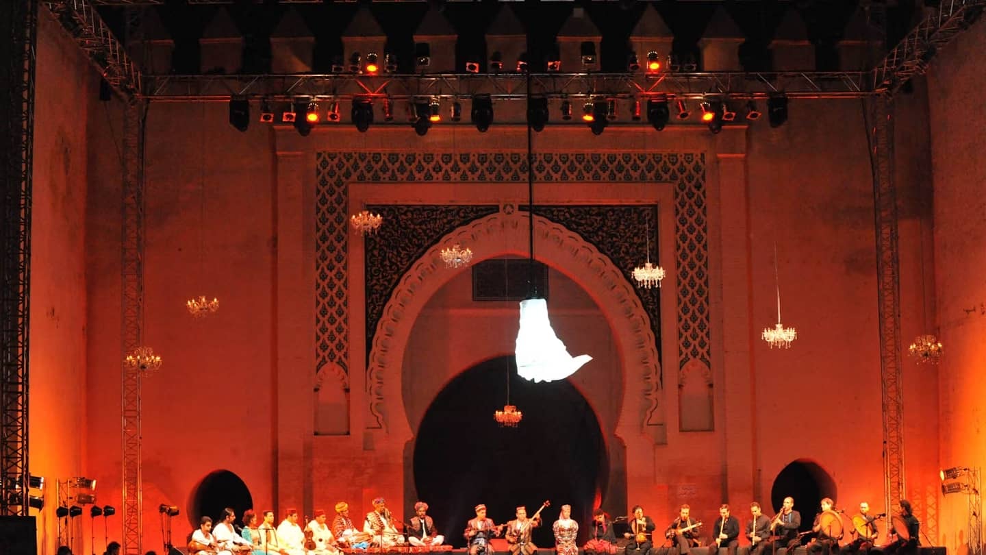 A musical performance at the Fes Festival of World Sacred Music, set against a grand backdrop of traditional Moroccan architecture.