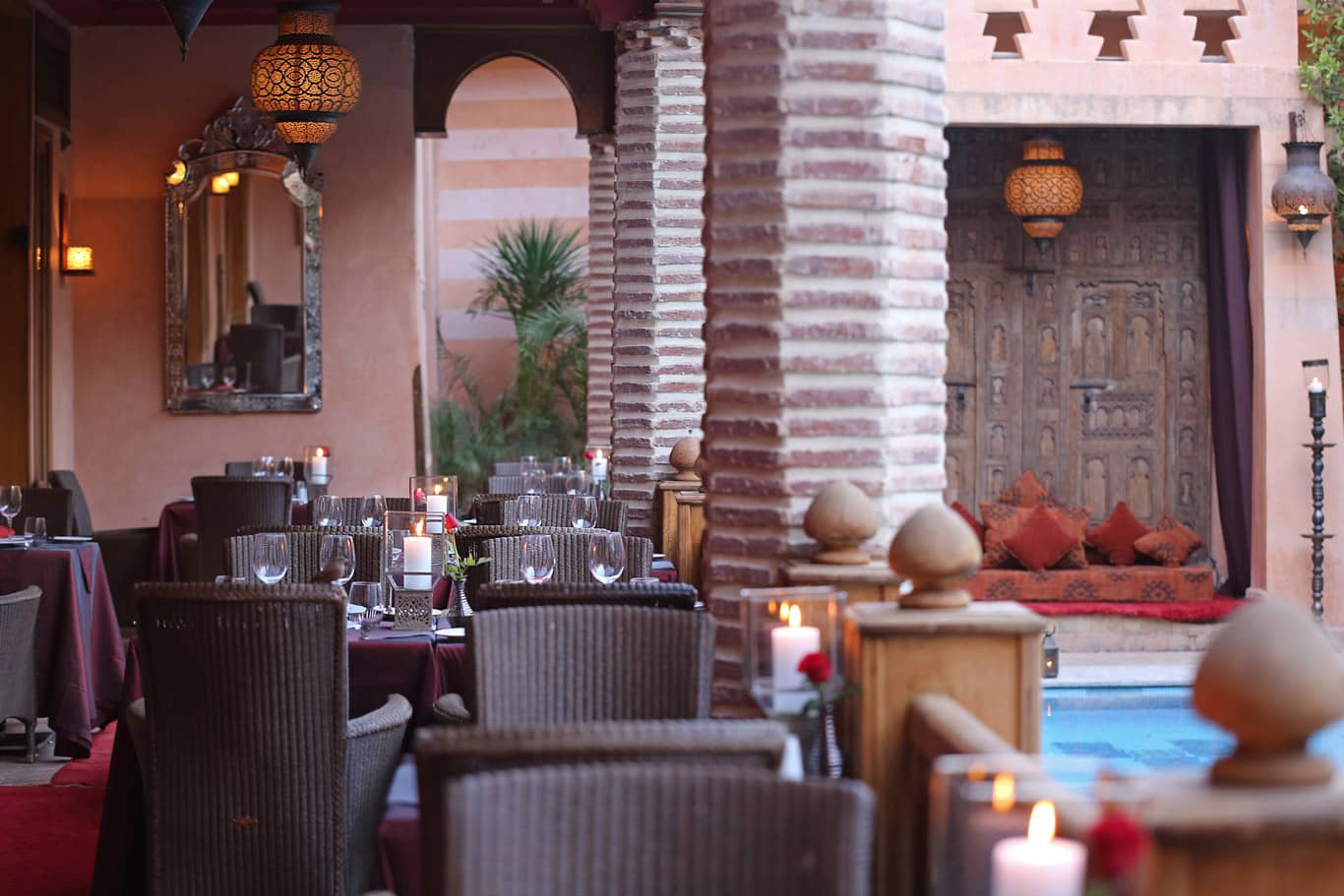 A cozy and elegant dining area in La Maison Arabe, Marrakesh, featuring traditional Moroccan decor and ambient lighting by the poolside.