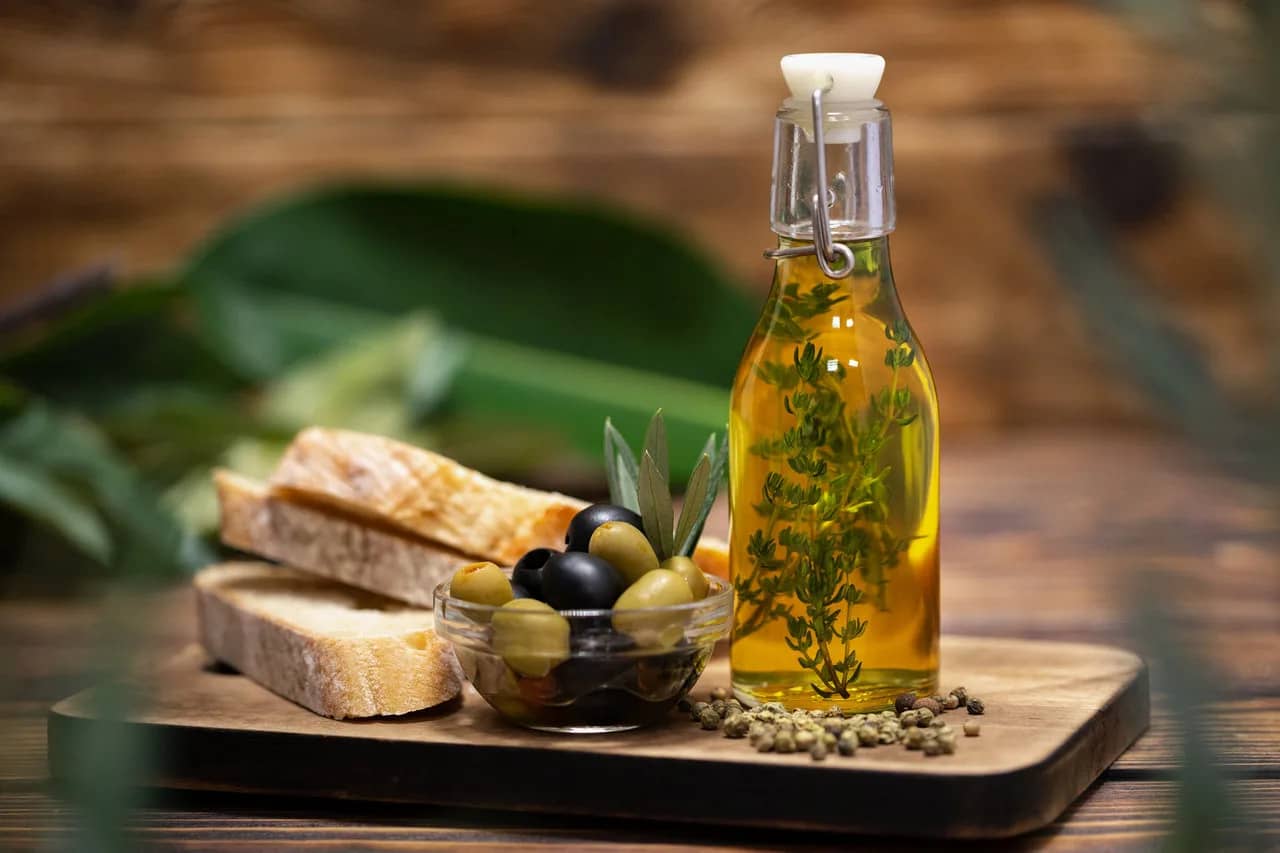 A delightful olive tasting setup in Morocco, featuring a bottle of infused olive oil, a bowl of assorted olives, and slices of fresh bread.