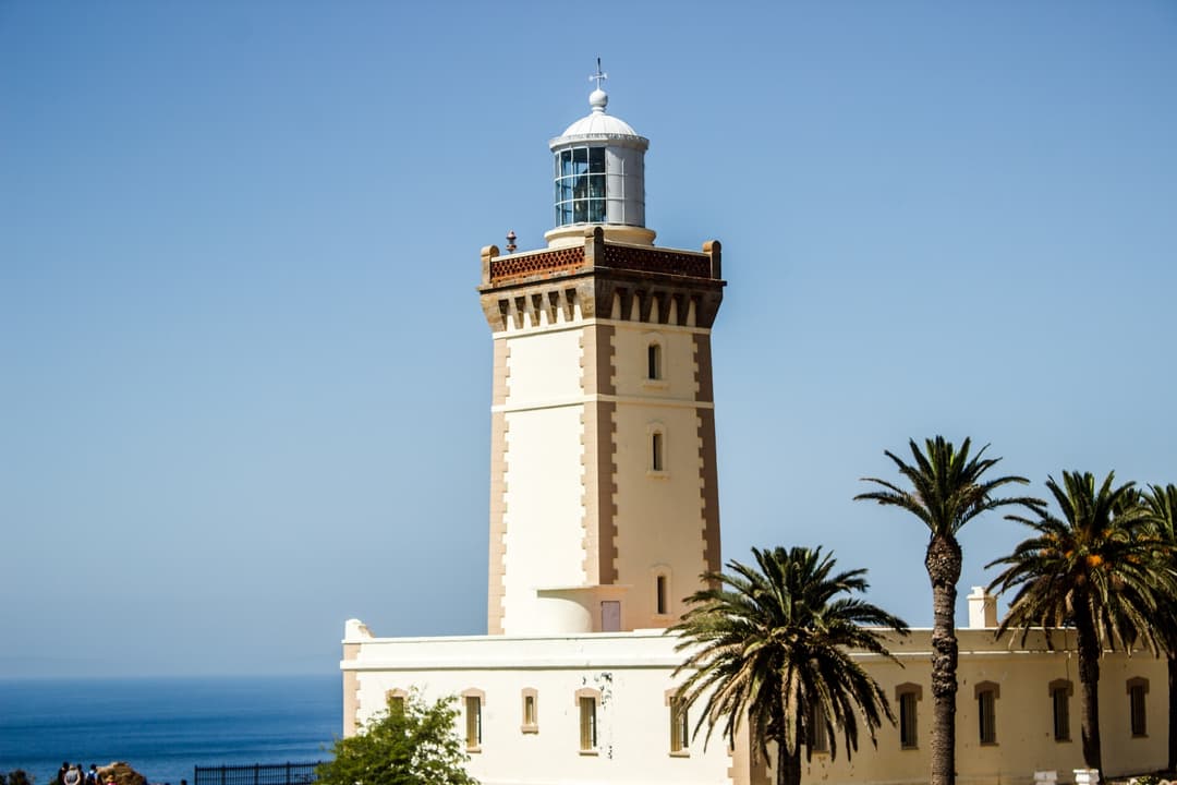 The Cape Spartel Lighthouse in Tangier stands majestically, with its traditional architecture set against a backdrop of clear blue skies and the sea.